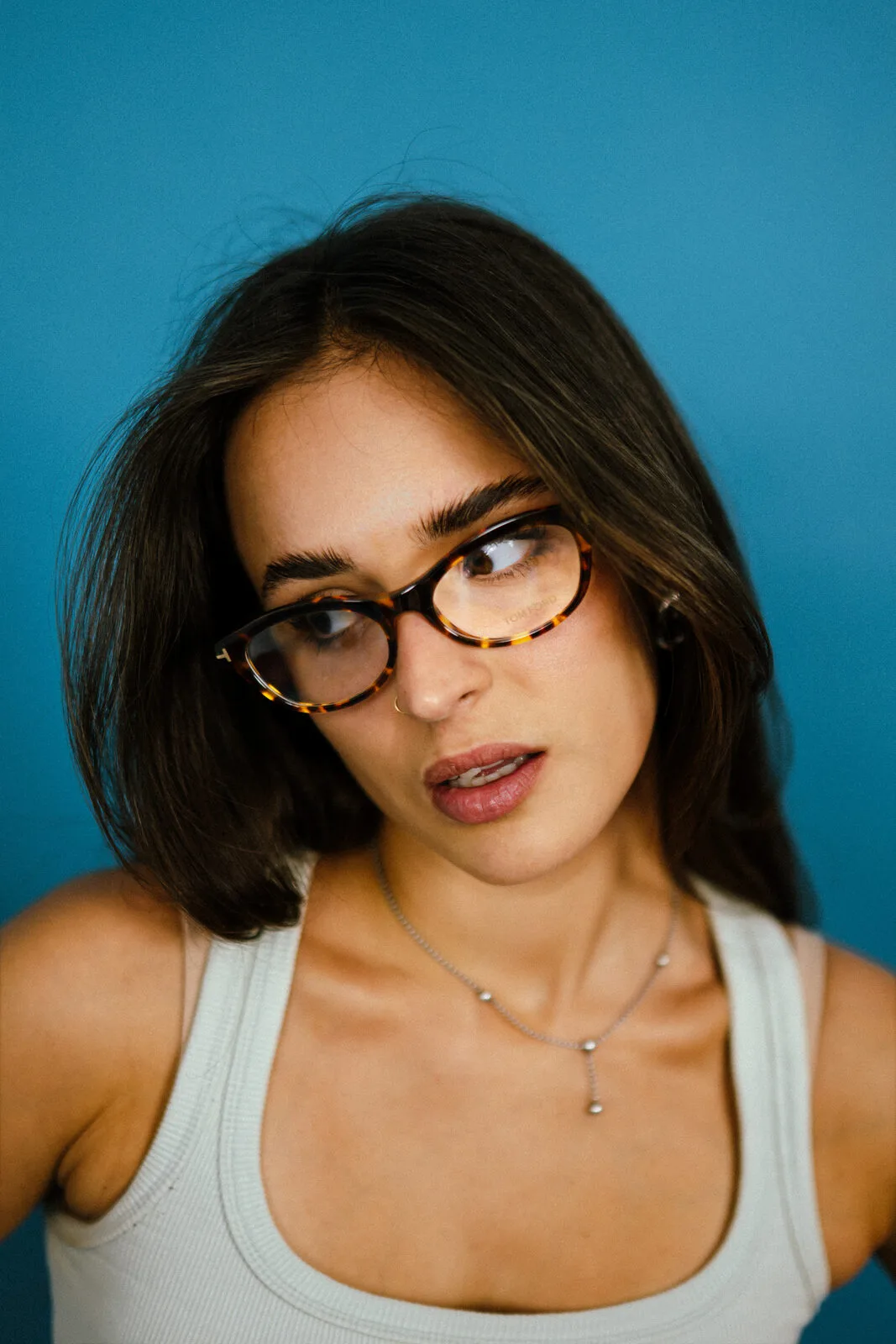 A customer in tortoiseshell frames against the Optirama blue